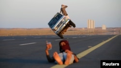 Saudi men perform a stunt known as "sidewall skiing" (driving on two wheels) as a youth takes a selfie in Tabuk, Saudi Arabia March 11, 2018. 