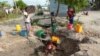 A woman fetches water from an unprotected source in Beira, Mozambique, Sunday, March, 31, 2019.