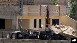Vehicles are parked inside the compound of a house where it is believed al-Qaida leader Osama bin Laden lived in Abbottabad, Pakistan on Monday, May 2, 2011.