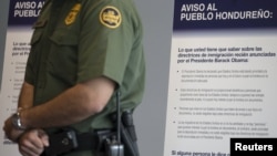 A U.S. Customs and Border Protection officer stands in front of a Spanish-language poster being used in a campaign to discourage illegal border crossings into the United States during a news conference at the Ysidro border crossing in San Ysidro, California, Aug. 18, 2015.