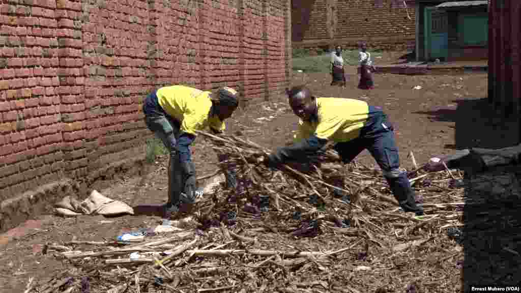 Deux jeunes employés de Briquettes du Kivu étalent au soleil les déchets organiques qu'ils ont tiré d'un champs après récolte, à Bukavu, en RDC, le 30 mai 2018. (VOA/Ernest Muhero)