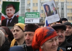 People hold banners of Vladimir Putin and Ramzan Kadyrov, as they take part in a rally marking the 13th anniversary of the adoption of the Constitution of Russian region of Chechnya, in the regional capital of Grozny, Russia on March 23, 2016.