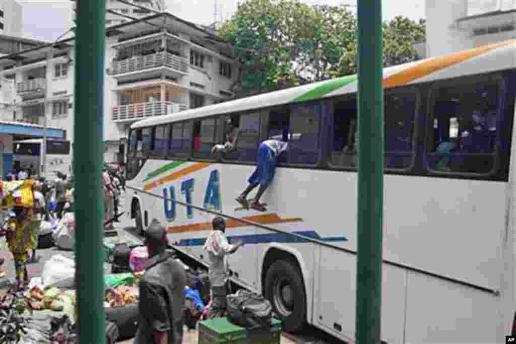 With possessions balanced on their heads, about 1,000 people frantically crowded around buses rented by Mali to evacuate its citizens from Abidjan, Ivory Coast, including a Malian man climbing into the window of a bus, March 25, 2011