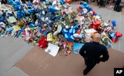 A policeman visits a makeshift memorial at the Dallas police headquarters, July 11, 2016, in Dallas.