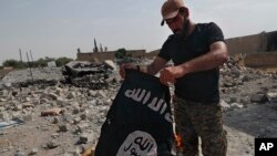 Seorang pejuang dari kelompok milisi Kristen Suriah membakar bendera ISIS di wilayah barat Kota Raqqa, di Suriah, pada 17 Juli 2017. (Foto: AP/Hussein Malla)