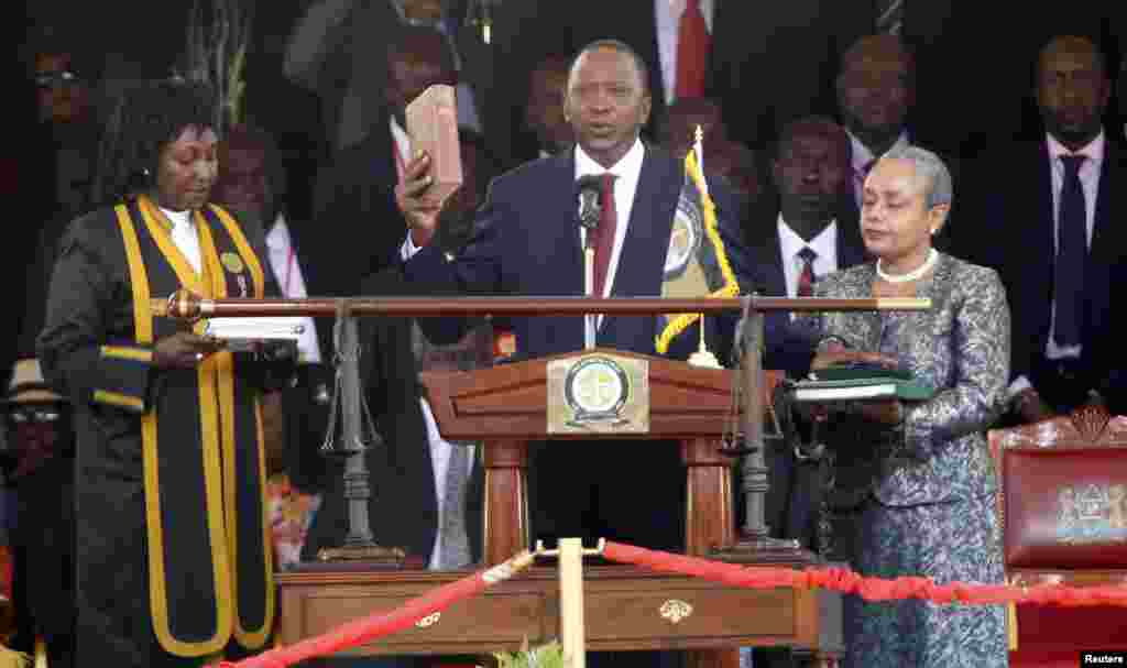 Kenya's President Uhuru Kenyatta takes the oath of office as his wife Margaret holds a bible during the official swearing-in ceremony at Kasarani Stadium in Nairobi, April 9, 2013. 