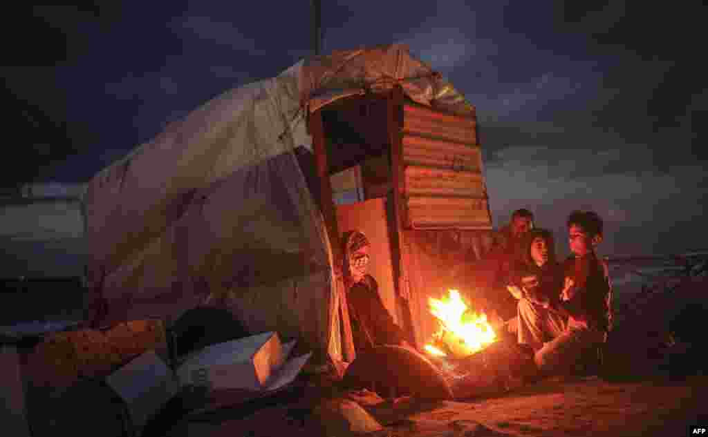 Palestinian children warm up around a fire by a shack along the beach in Gaza City.