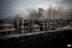 FILE - Smoke is seen rising over Saif Al Dawla district, in Aleppo, Syria.