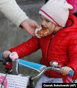 A little girl indulges in Poland's tradition of eating jam-filled doughnuts, or Paczki, in Warsaw, Poland, Feb. 27, 2014.