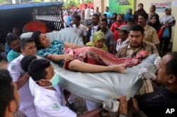 Hospital workers and family members carry a woman injured in an earthquake at a hospital in Pidie, Aceh province, Indonesia, Dec. 7, 2016.