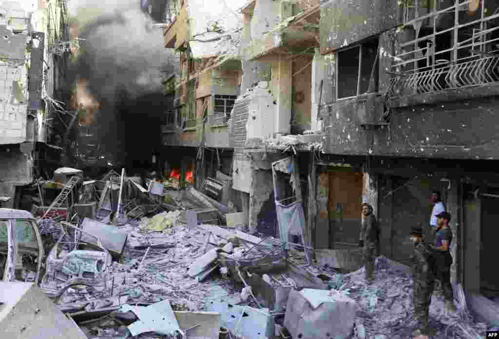 Syrian government forces walk down a destroyed street in the Hajar al-Aswad area on the southern outskirts of Damascus after the army announced it was in complete control of the capital and its outskirts for the first time since 2012, following the ousting of the Islamic State group from a last pocket of resistance.