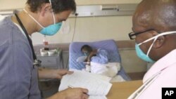 A doctor (left) and a nurse discuss the condition of a patient infected with both HIV and tuberculosis in a hospital in South Africa 