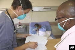 A doctor (left) and a nurse discuss the condition of a patient infected with both HIV and tuberculosis in a hospital in South Africa