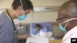 A doctor (left) and a nurse discuss the condition of a patient infected with both HIV and tuberculosis in a hospital in South Africa .