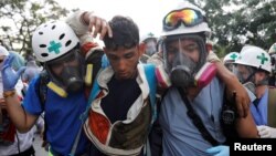 Para relawan menolong pengunjuk rasa yang terluka (tengah) saat melakukan aksi demo menentang Presiden Nicolas Maduro di Caracas, Venezuela, 24 April 2017. (REUTERS/Carlos Garcia Rawlins).