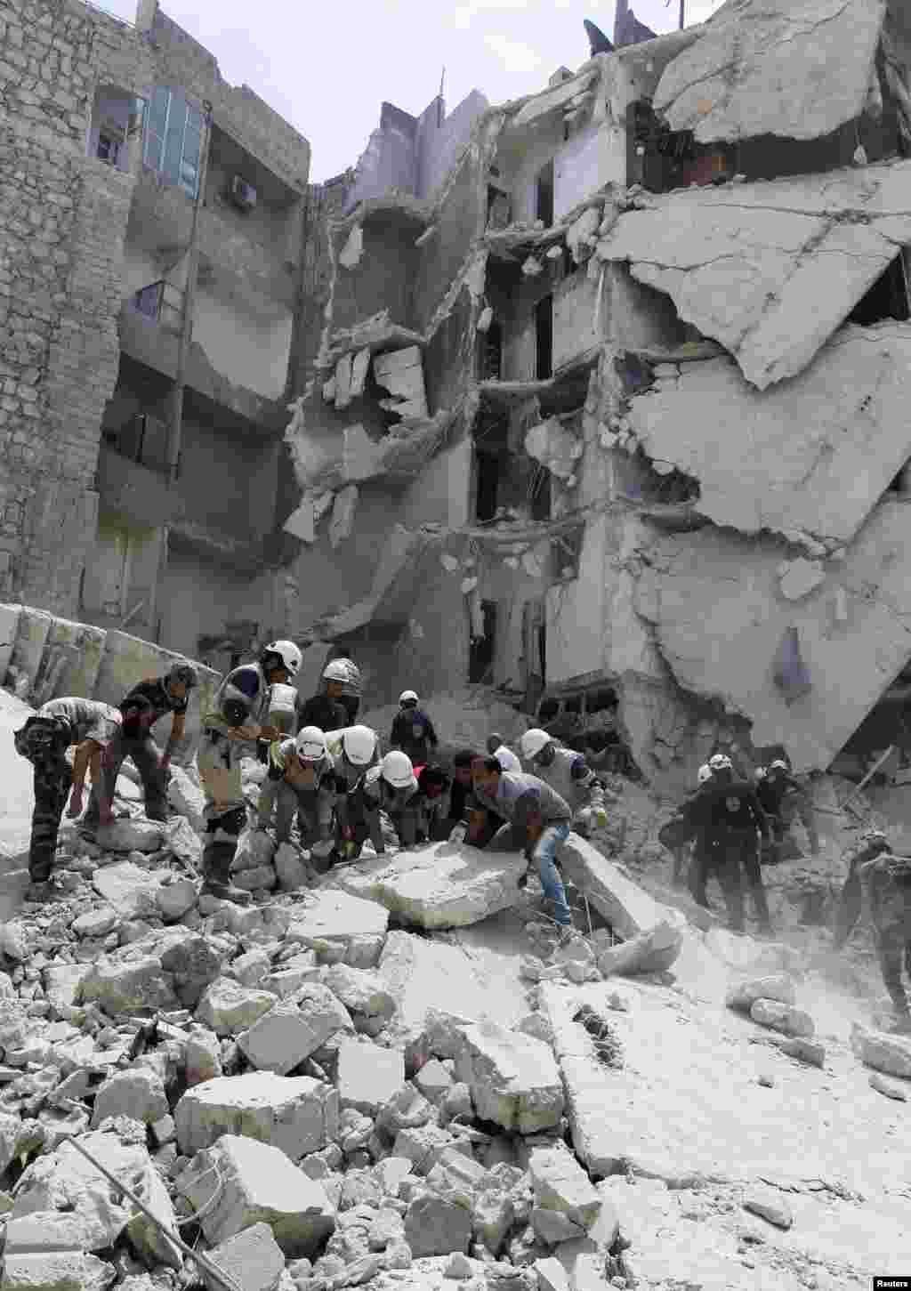 Rescue workers, rebel fighters and civilians search for survivors at a site hit by what activists said was a barrel bomb dropped by forces loyal to President Bashar al-Assad, al-Qarlaq, Aleppo, May 29, 2014.