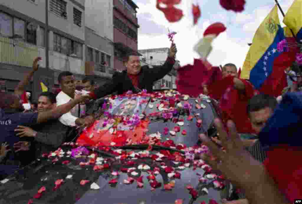 Venezuela's President Hugo Chavez, top, greets supporters during a caravan from Miraflores government palace to Simon Bolivar airport in Caracas, Venezuela, Friday, Feb. 24, 2012. Venezuelan President Hugo Chavez is on his way to Cuba to have a tumor remo