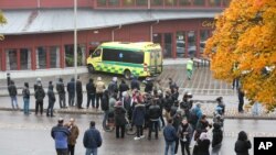 A crowd gathers outside, as emergency services attend the scene of a sword attack by a masked man at the Kronan school in Trollhattan, Sweden, Oct. 22, 2015. At least six people were injured, and the offender was shot by the police. 
