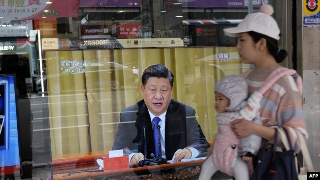 2019年1月2日,台湾新北市,一位母亲带着孩子经过一台电视,上面显示中国领导人习近平就台湾问题发表讲话。