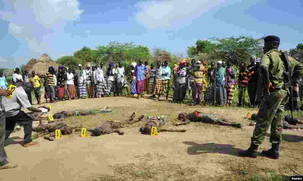 Wakazi na polisi watizama miili ya wanaotuhumiwa ni washambulizi kutoka kabila la Pokomo, kufuatia mapambano ya kikabila katika kijiji cha Kipao wilaya ya Tana River Delta kusini mashariki ya Kenya. Dec. 21, 2012. 