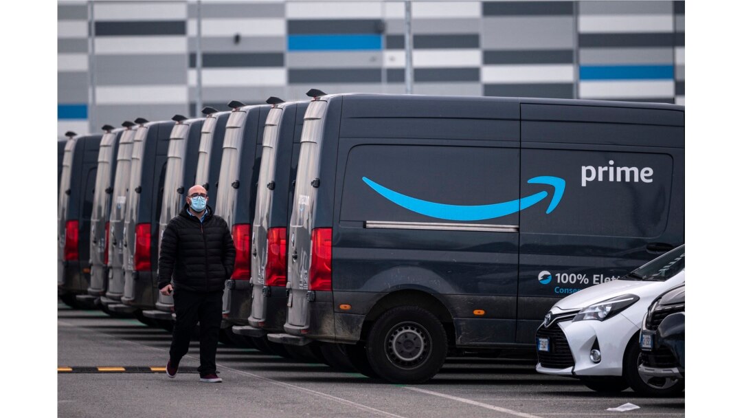 Seorang karyawan Amazon berjalan di dekat barisan truk layan antar Amazon Prime i Brandizzo, dekat Turin, 22 Maret 2021.