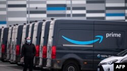 An Amazon employee walks by an Amazon Prime delivery truck in the company's premises in Brandizzo, near Turin. Taken 3.21.2022