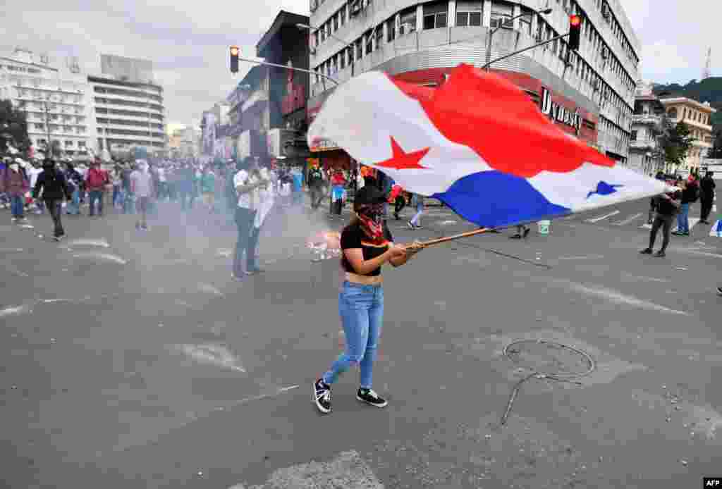 Estudiantes, miembros de organizaciones civiles y sindicatos protestan con una bandera nacional panameña contra las reformas constitucionales propuestas.