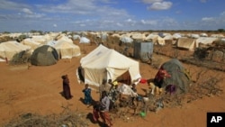 Refugees stand outside their tent at the Ifo Extension refugee camp in Dadaab, Kenya, October 19, 2011.