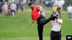 FILE - Tiger Woods makes an awkward follow through after hitting from the lip of a fairway bunker on the second hole during the final round of the Bridgestone Invitational golf tournament Sunday, Aug. 3, 2014.
