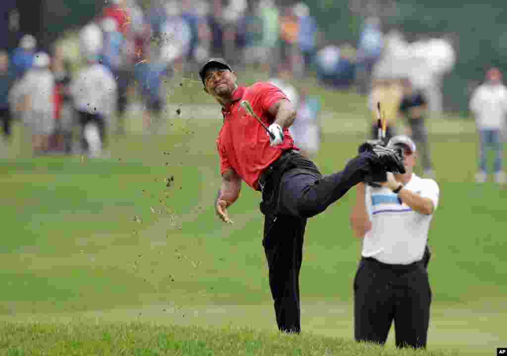 Tiger Woods makes an awkward follow through after hitting from the lip of a fairway bunker on the second hole during the final round of the Bridgestone Invitational golf tournament at Firestone Country Club in Akron, Ohio, USA.