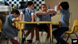 In this Oct. 13, 2017 file photo, children discuss their thoughts about Hurricane Maria at Ramon Marin Sola Elementary School in Guaynabo, Puerto Rico. (AP Photo/Carlos Giusti, File)