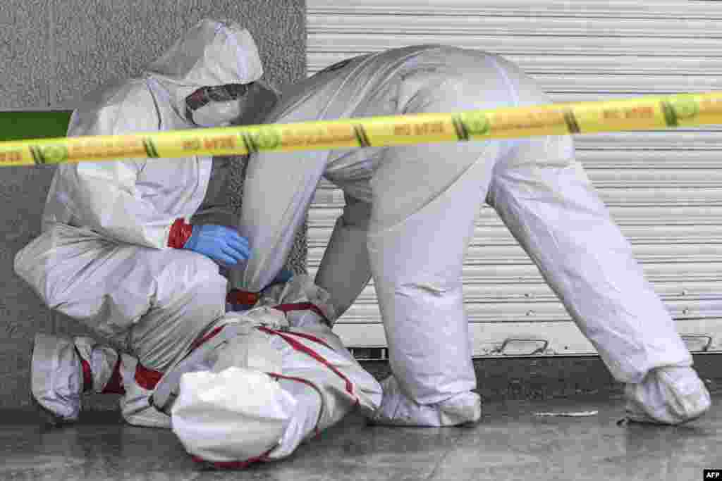 Police officers wearing protective clothing remove the dead body of a man who died in the street in Medellin, Colombia, May 6, 2020, during the COVID-19 coronavirus pandemic.