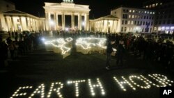 Activistas del Fondo Mundial para la Vida Silvestre encienden luces frente a la iluminada Puerta de Brandenburgo para celebrar la Hora de la Tierra, en Berlín, Alemania, el sábado 30 de marzo de 2019. 