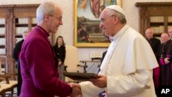 Paus Fransiskus (kanan) saling bertukar hadiah dengan kepala gereja Anglikan, Uskup Agung Canterbury Justin Welby dalam pertemuan di Vatikan (14/6). 