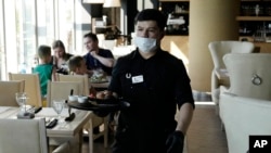 A waiter wearing a face mask and gloves to protect against coronavirus, serve customers in a restaurant "Meat and fish" in Moscow, Russia, June 18, 2021.