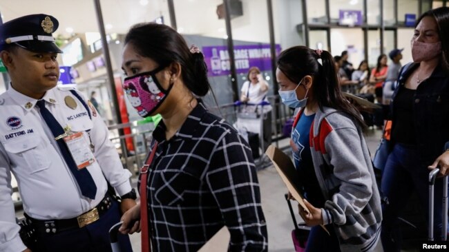 2020年2月18日，戴着口罩的菲律宾劳工在马尼拉国际机场准备登机出国。