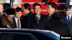 2013年2月21日，日本首相安倍晋三(中)抵达华盛顿附近安德鲁斯空军基地，美国首席礼宾官卡普丽奇娅•马歇尔(左)到机场迎接。
