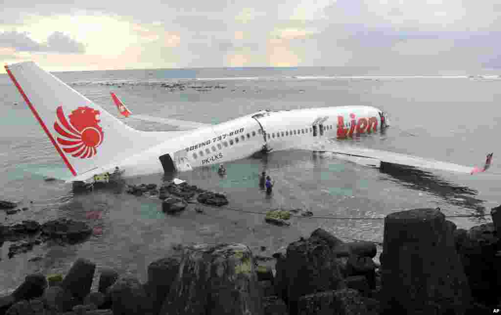 In this photo released by Indonesian Police, the wreckage of a crashed Lion Air plane sits on the water near the airport in Bali, Indonesia. The plane carrying more than 100 passengers and crew overshot a runway on the resort island of Bali and crashed into the sea, injuring nearly two dozen people, officials said.