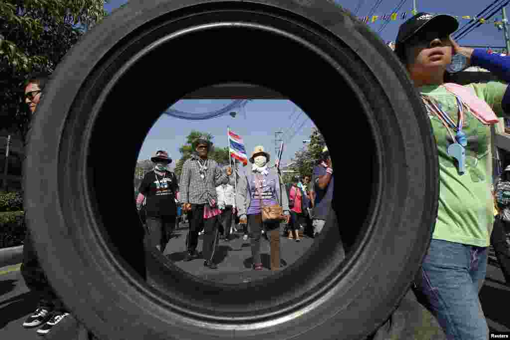 Anti-government protesters march past one of their roadblocks made of tires in central Bangkok, Thailand.