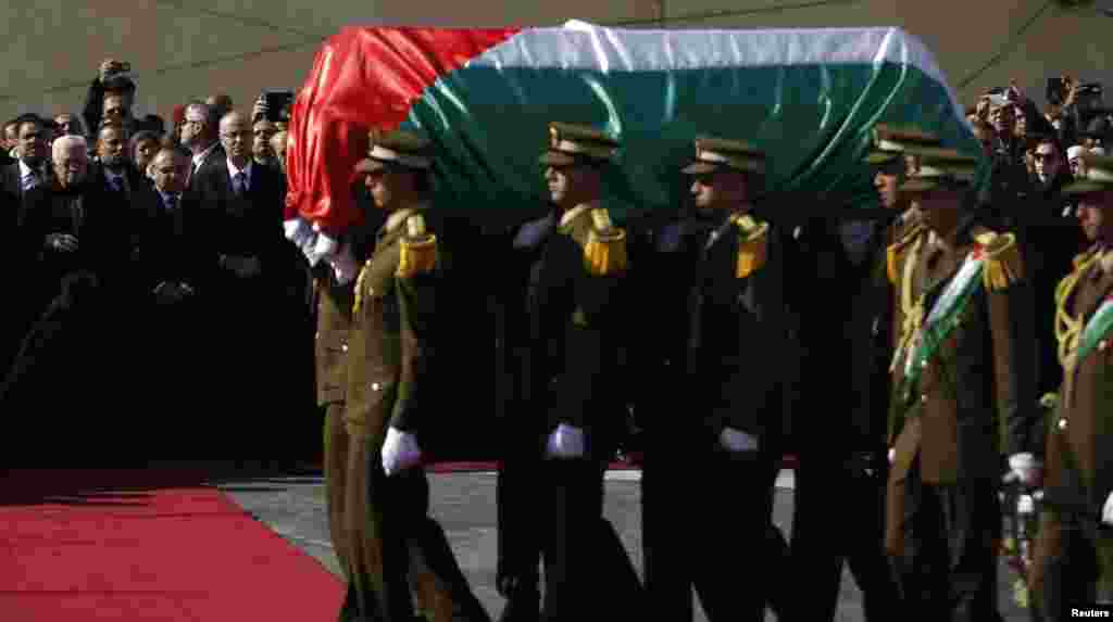Palestinian President Mahmoud Abbas (back left) watches as Palestinian honor guards carry the coffin containing the body of Palestinian Minister Ziad Abu Ein during his funeral in the West Bank city of Ramallah, Dec. 11, 2014.