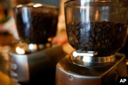 FILE - Coffee beans are seen in grinders at Vigilante Coffee, in College Park, Md., Sept. 1, 2021. A confluence of supply chain problems, drought, frost and inflation all point to higher coffee prices.