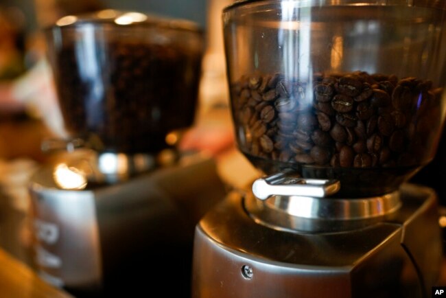 FILE - Coffee beans are seen in grinders at Vigilante Coffee, in College Park, Md., Sept. 1, 2021. A confluence of supply chain problems, drought, frost and inflation all point to higher coffee prices.