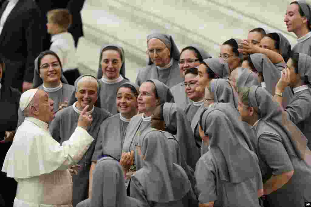 Pope Francis talks with a group of nuns during his weekly general audience, in the Pope Paul VI hall, at the Vatican.
