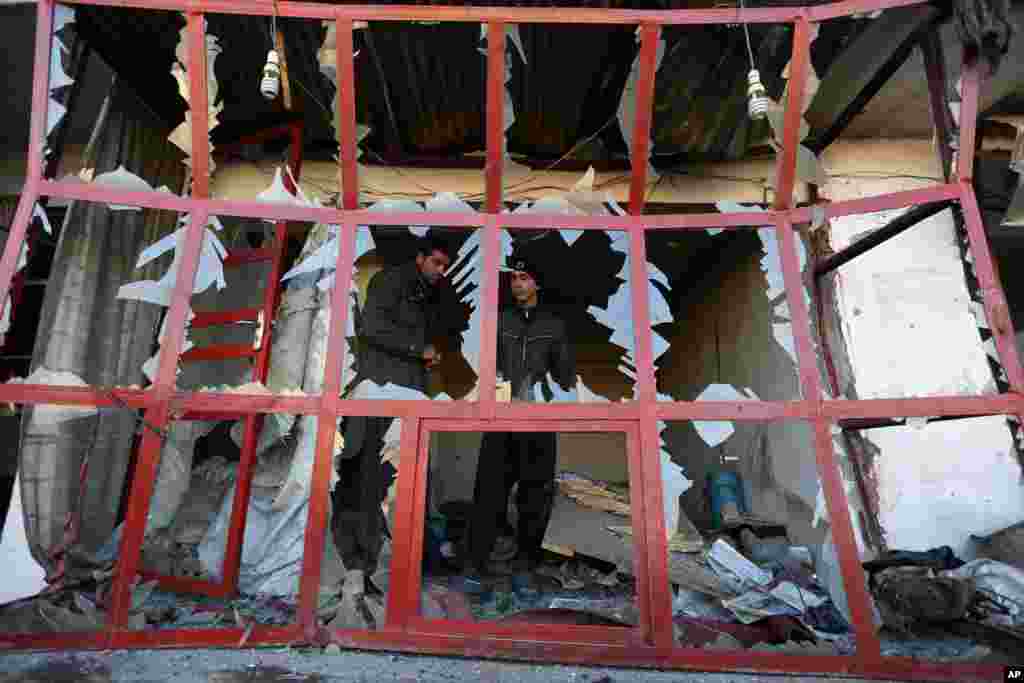 An Afghan shopkeeper peers out through the broken windows of his shop near the site of a suicide car bomb attack in Kabul.