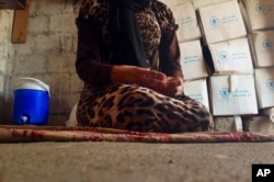 FILE - A 15-year-old Yazidi girl who had been captured by the Islamic State group and forcibly married to a militant in Syria, but later escaped, sits on the floor of her family's house during an interview in Maqluba, Iraq, Oct. 8, 2014.