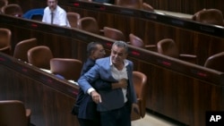A Knesset usher removes Jamal Zahalka, an Israeli Arab member of the Knesset representing the Balad party, who was protesting the passage of a contentious bill, during a Knesset session in Jerusalem, Thursday, July 19, 2018. Israel's parliament approved a controversial piece of legislation early Thursday that defines the country as the nation-state of the Jewish people. Opponents and rights groups have criticized the legislation, warning that it will sideline minorities such as the country's Arabs.