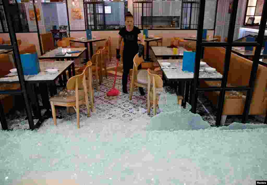 An employee clears shattered glass after anti-government protesters vandalized a restaurant during a demonstration at New Town Plaza shopping mall in Hong Kong, China.