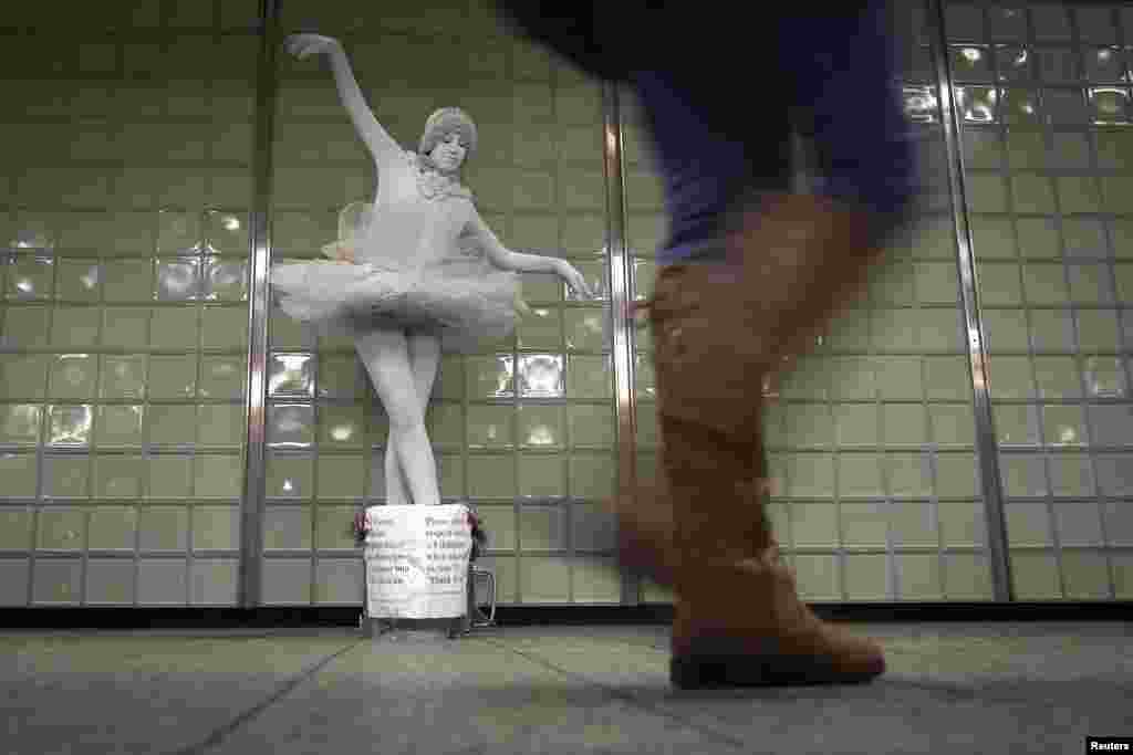 Living statue ballerina Therisa Barber-Shaw performs for tips in the Times Square subway station in the Manhattan borough of New York.