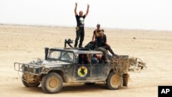 Iraqi soldiers flash victory signs after regaining control of the Ramadi Stadium and the neighboring al-Bugleeb area, Oct. 6, 2015.