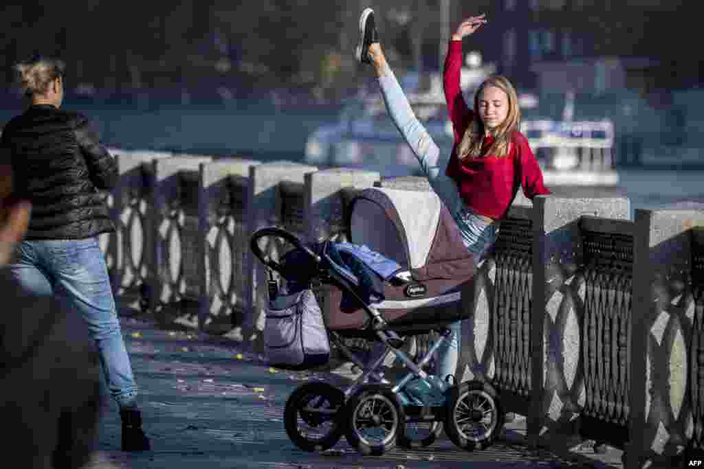 A girl stretches next to a pram on the embankment of the Moskva river in Moscow, on Oct.18, 2018. The European part of Russia enjoys unusually warm weather for the season with temperatures reaching up to 22 degrees centigrade.